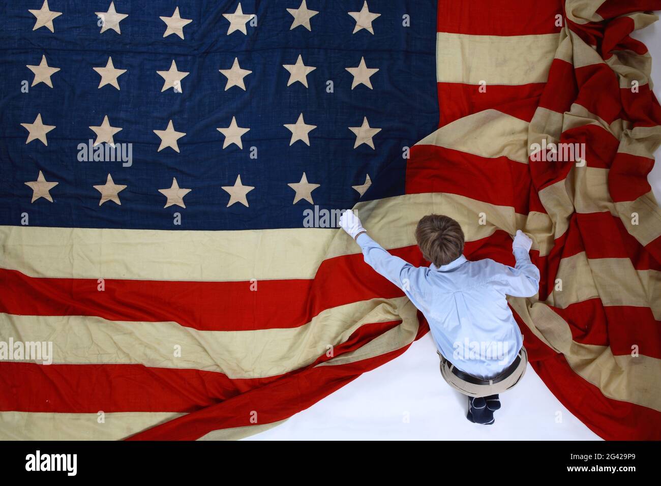 Un homme qui se replie sur un drapeau américain géant. Tourné au Texas, États-Unis. Banque D'Images