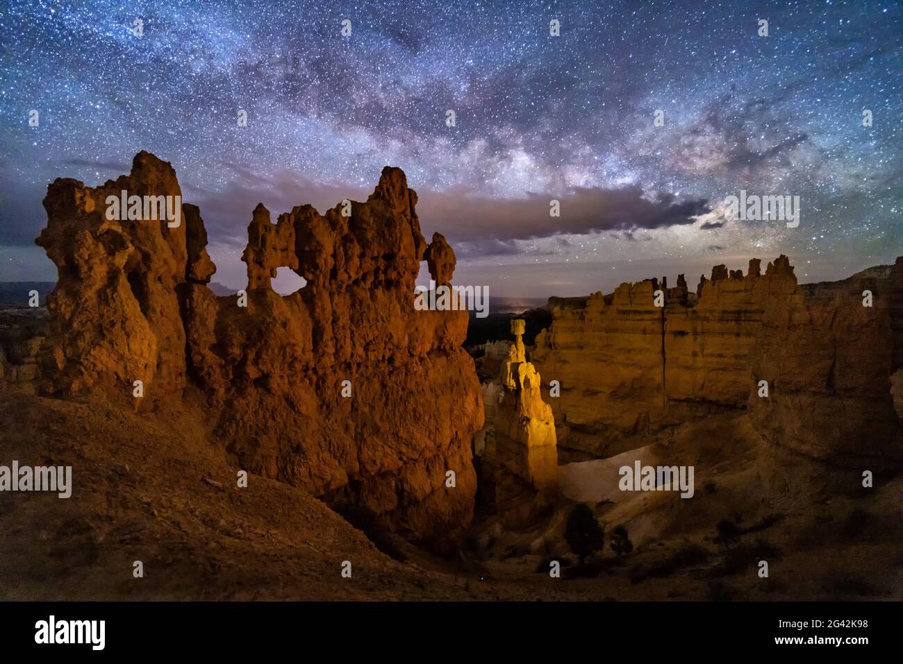 Un hoodoo avec de petites fenêtres et Thor's Hammer contre un ciel nocturne avec des nuages et la voie lactée sous Sunset point dans le parc national de ryce Canyon, Utah. Banque D'Images