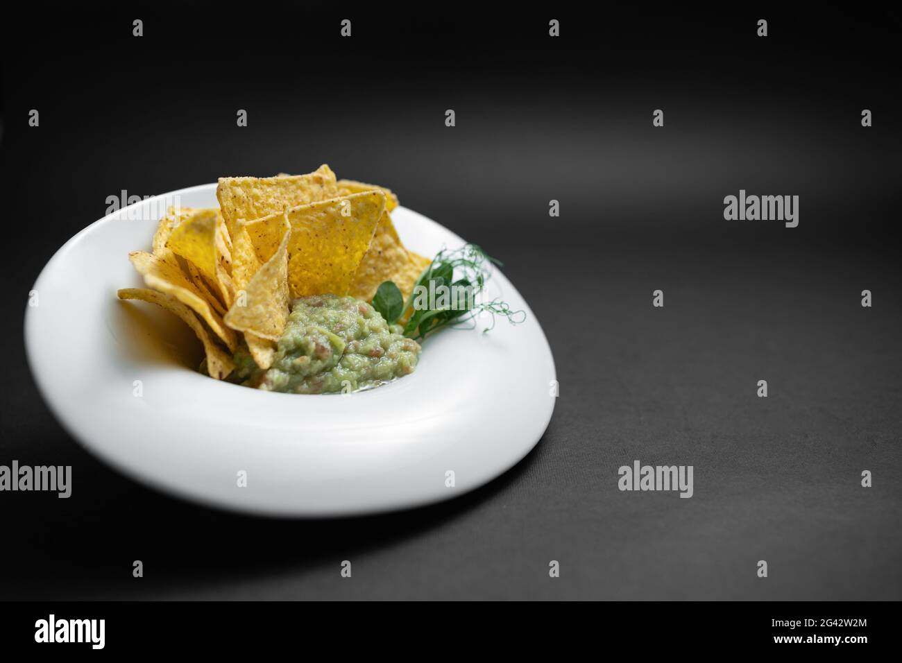 gros plan de la sauce guacamole dans un bol avec avocat et nachos sur fond noir Banque D'Images