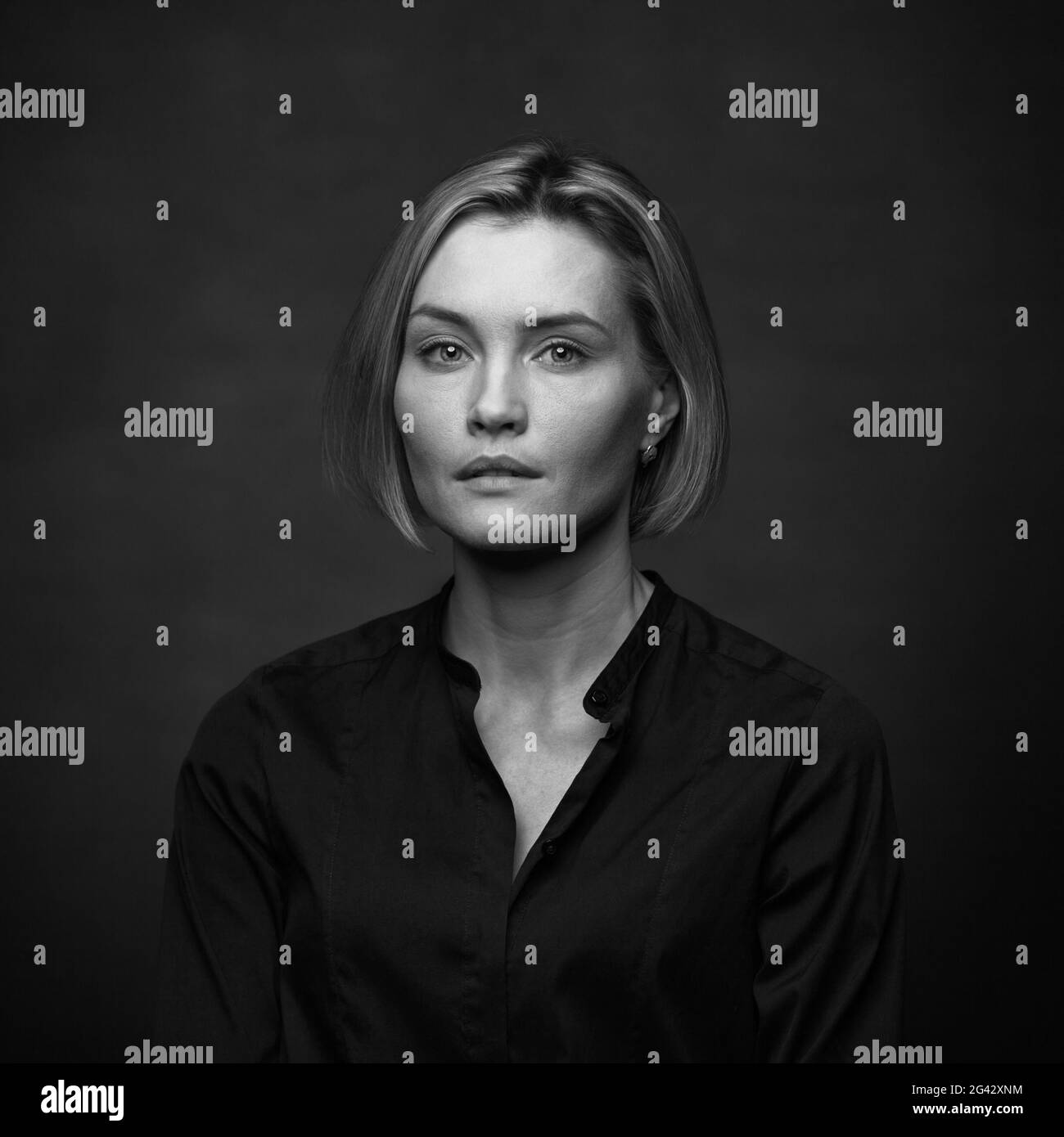 Belle femme d'âge moyen sur fond gris dans un chemisier noir. Banque D'Images