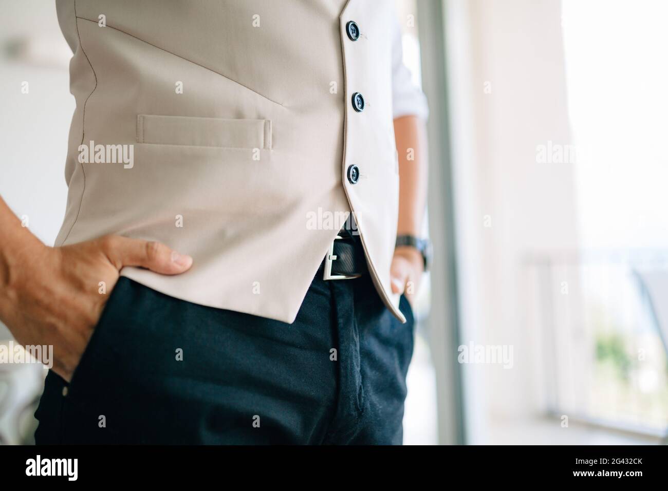 Un homme tenant ses mains dans ses poches de pantalon une chambre d'hôtel tout en préparant une cérémonie de mariage Banque D'Images