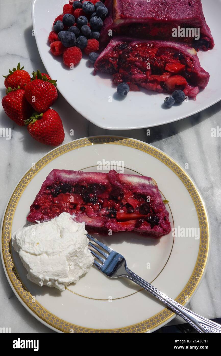 Une tranche d'une terrine maison de pudding anglais d'été avec de la crème fouettée fraîche chattily. Banque D'Images