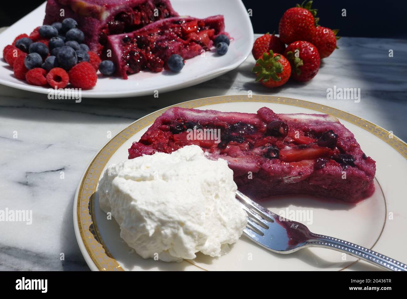 Une tranche d'une terrine maison de pudding anglais d'été avec de la crème fouettée fraîche chattily. Banque D'Images