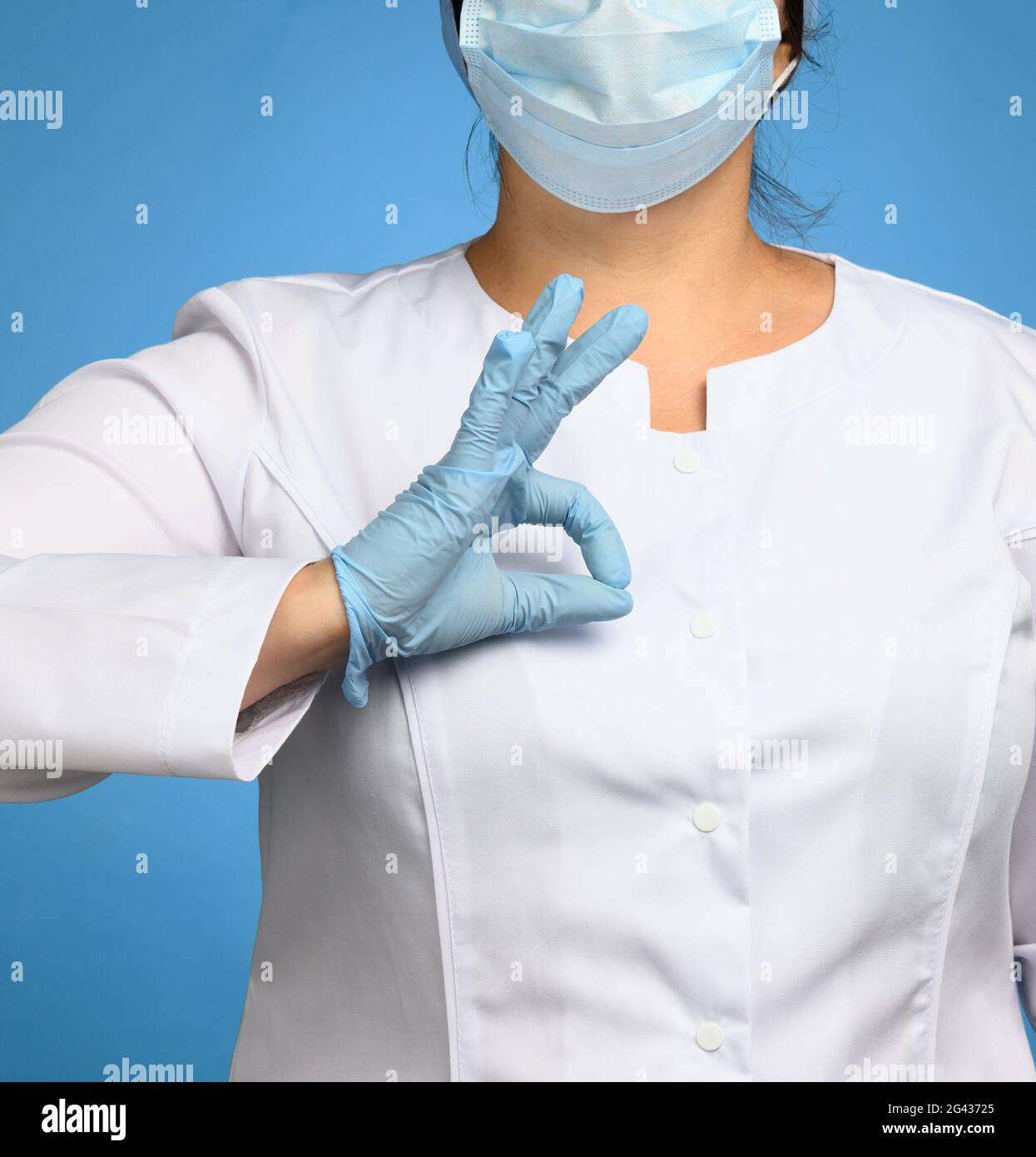 Femme en manteau blanc, portant des gants médicaux en latex bleus sur ses mains Banque D'Images