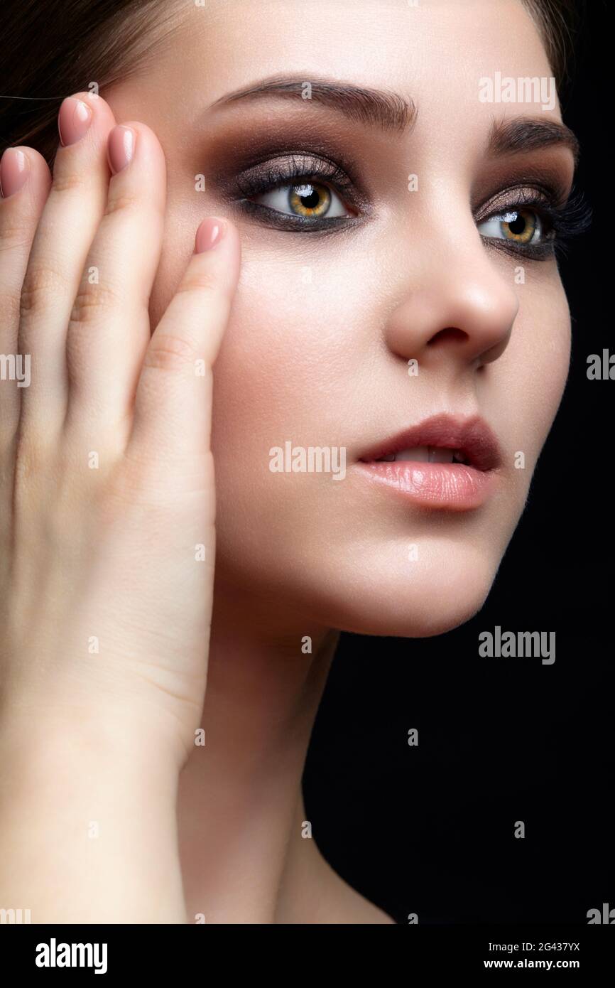 Portrait de beauté de la jeune femme. Petite fille Brunette avec maquillage de soirée et robe noire Banque D'Images