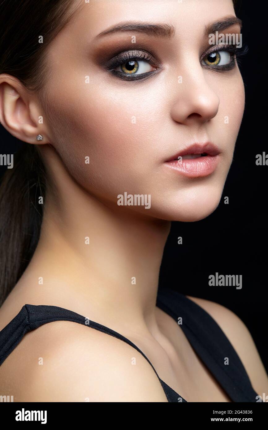 Portrait de beauté de la jeune femme. Petite fille Brunette avec maquillage de soirée et robe noire Banque D'Images