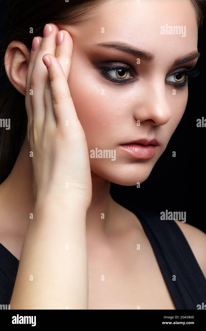 Portrait de beauté de la jeune femme. Petite fille Brunette avec maquillage de soirée et robe noire Banque D'Images