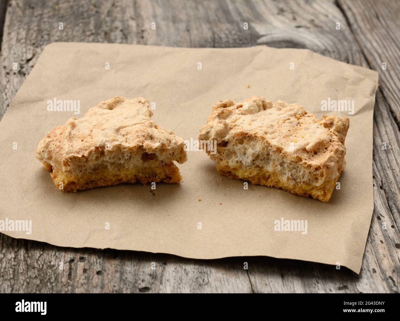 Des biscuits cuits carrés se trouvent sur un morceau de papier, une table en bois grise, des biscuits polis Banque D'Images