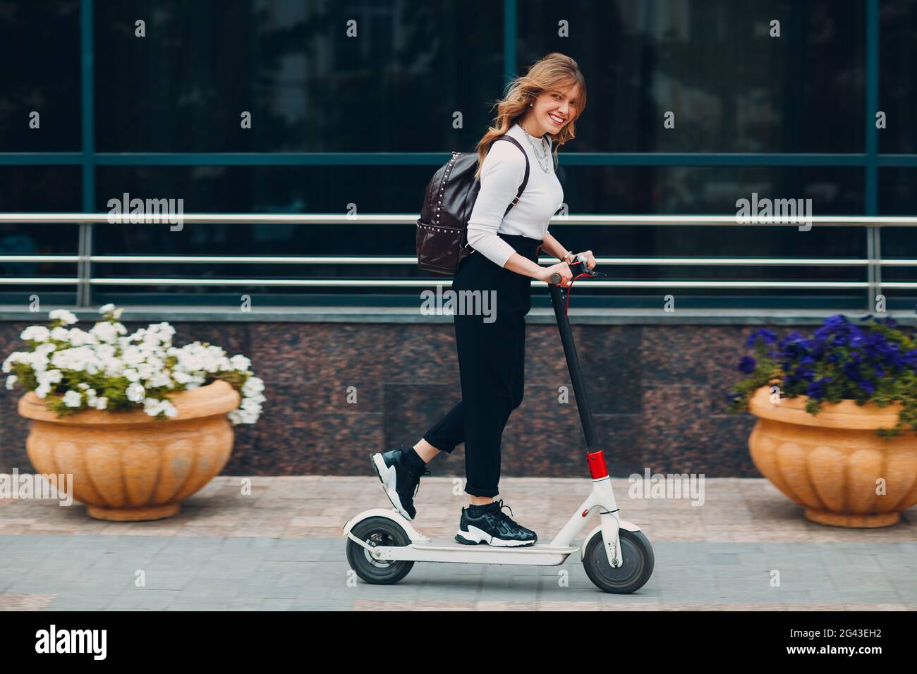 Jeune femme conduisant un scooter électrique à la ville Banque D'Images