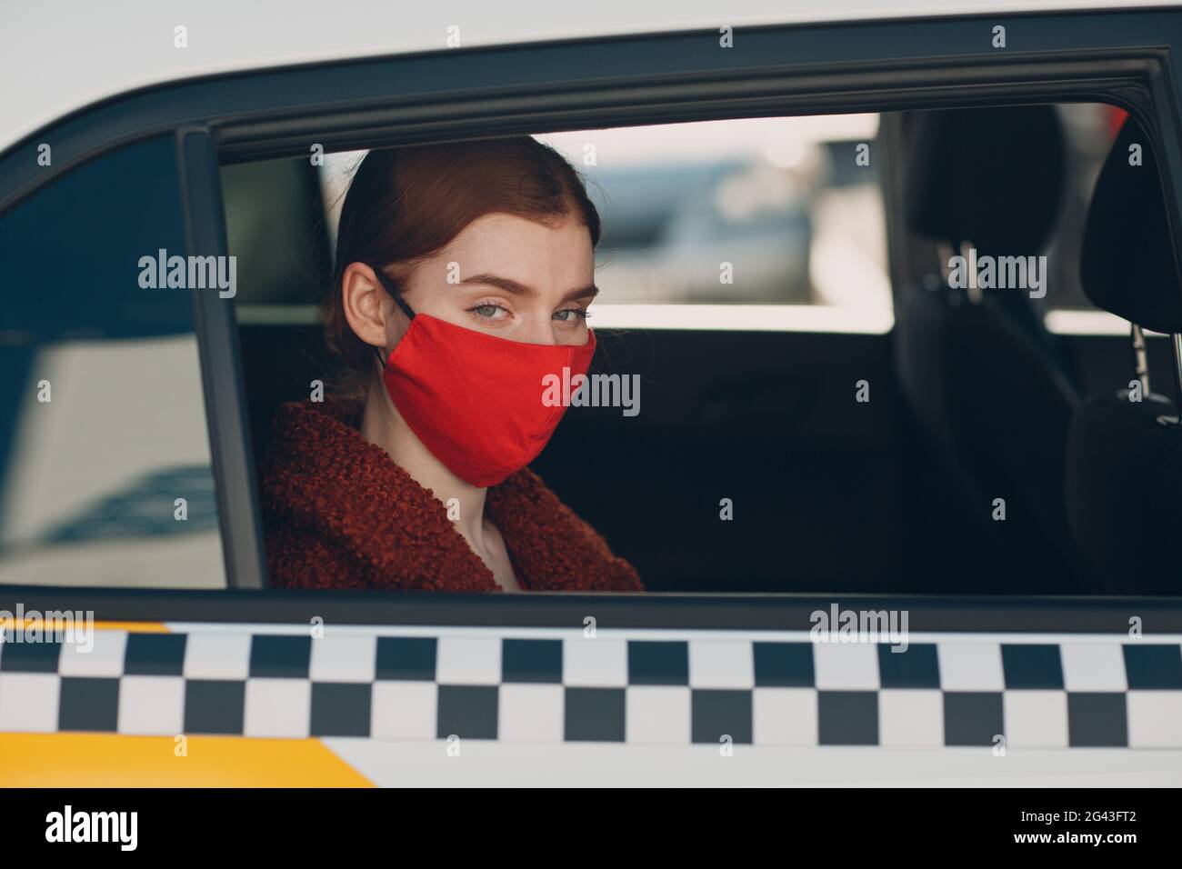 Une jeune femme passager prend un trajet en voiture de taxi pendant la quarantaine pandémique du coronavirus. Femme portant un visage médical stérile ma Banque D'Images