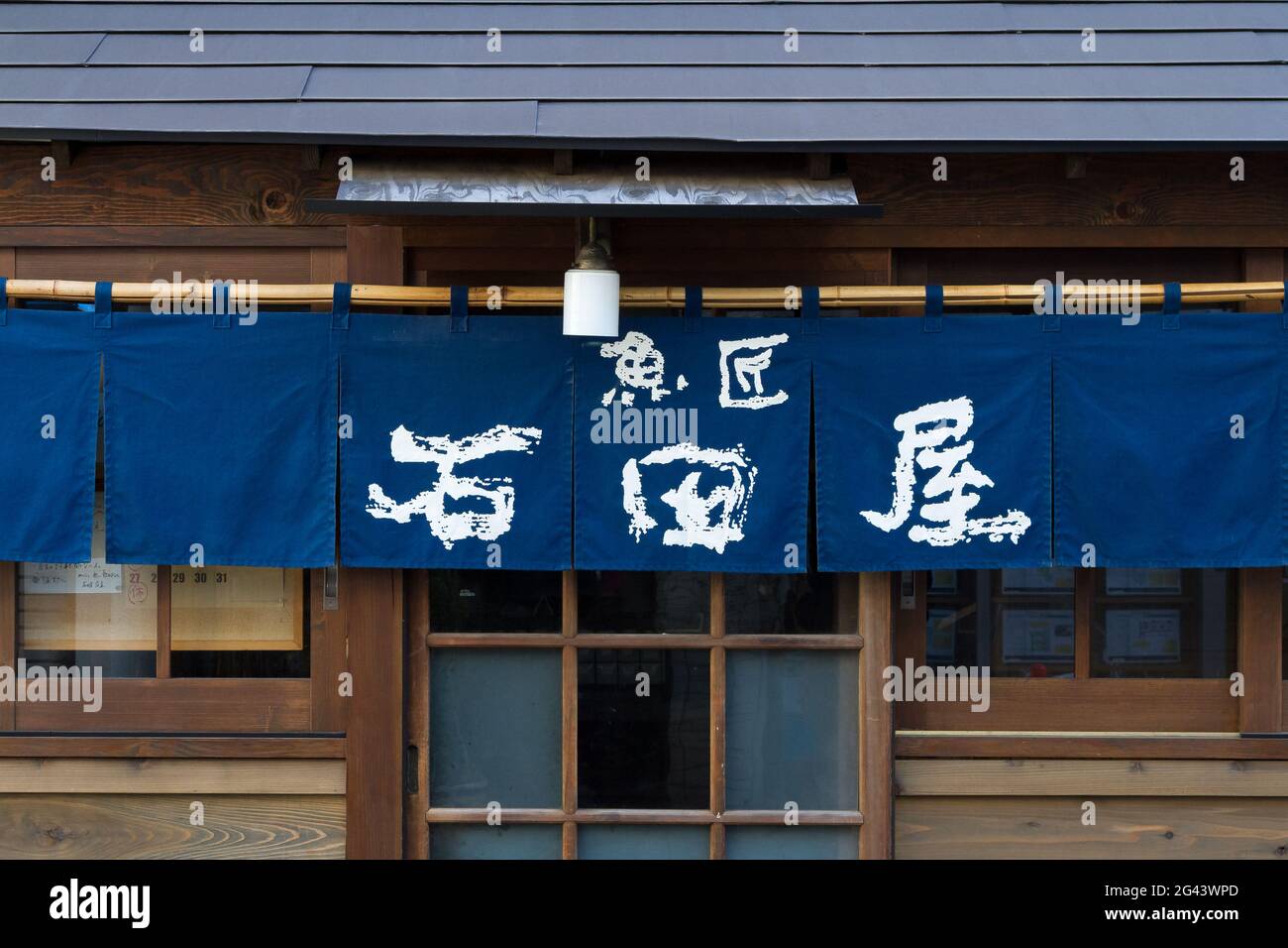 Rideaux noren au-dessus d'une porte d'un restaurant dans un ancien bâtiment en bois à Matsubara, Setagaya, Tokyo, Japon. Banque D'Images