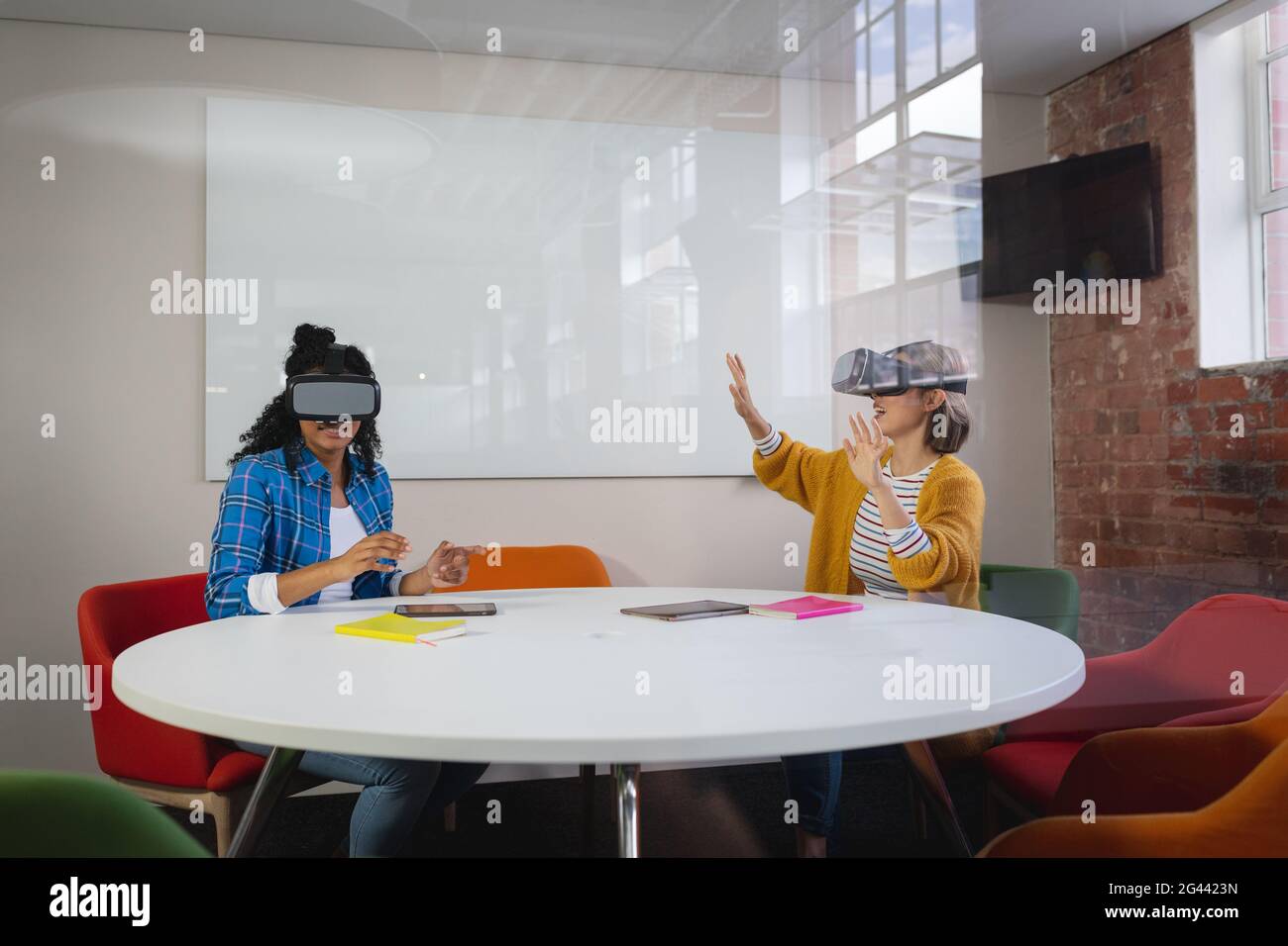 Des collègues féminins divers assis au travail portant un appareil de réalité virtuelle et de jouer Banque D'Images