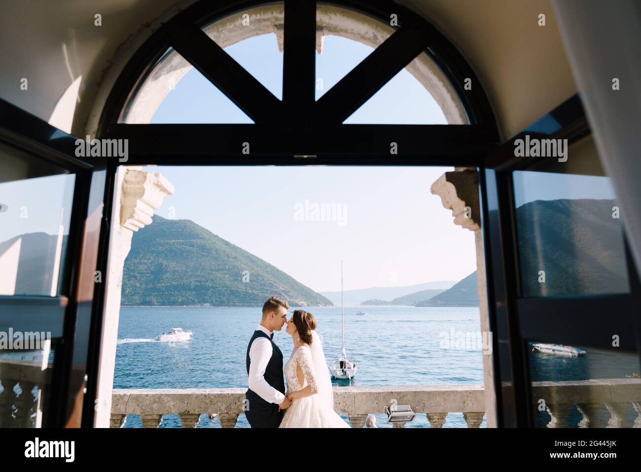 La mariée et le marié sont debout sur le balcon de l'hôtel donnant sur la mer, un regard à travers la vieille fenêtre ouverte. Les arts plastiques avec Banque D'Images