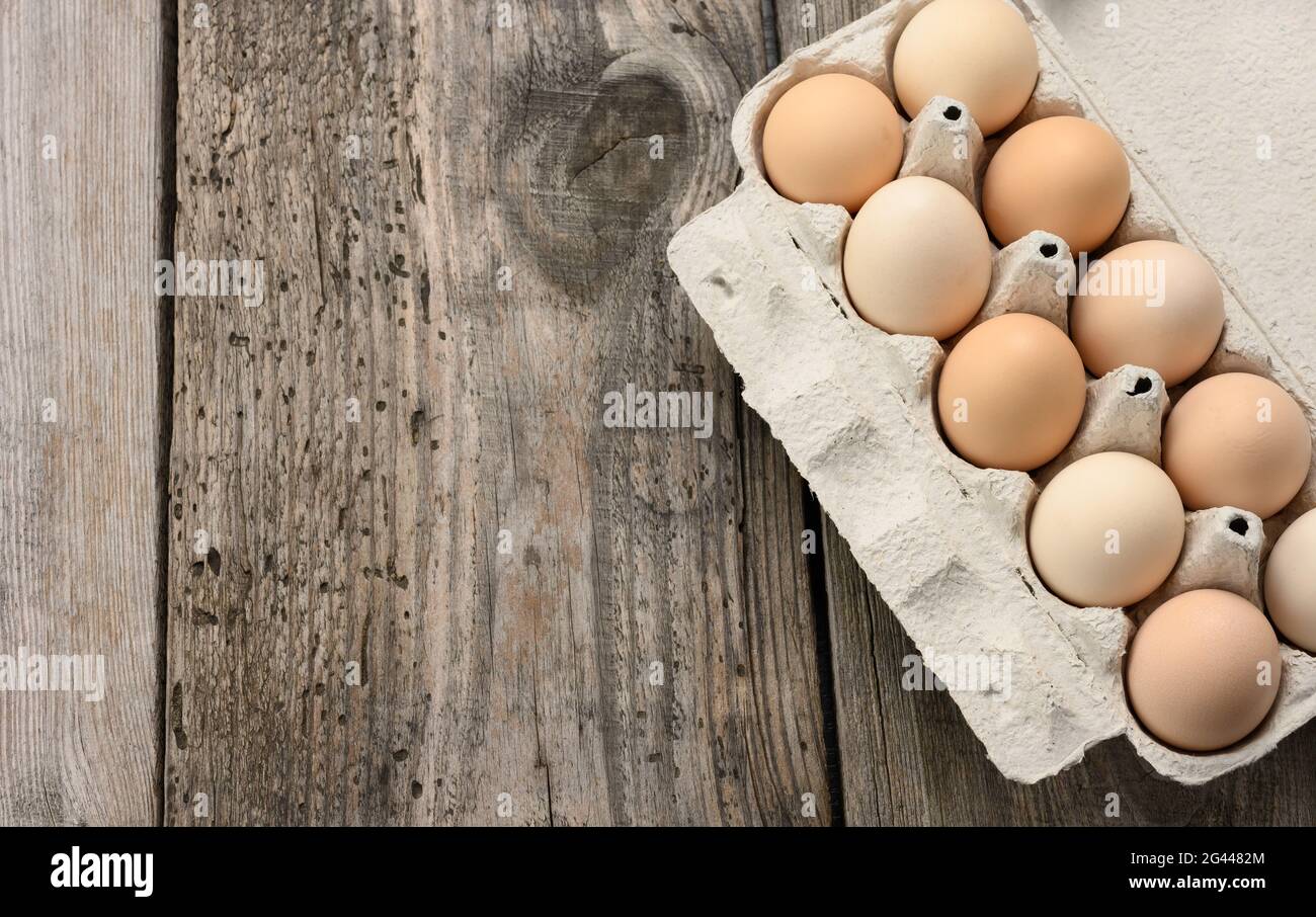 Oeufs entiers frais dans un emballage en papier sur fond de bois gris Banque D'Images