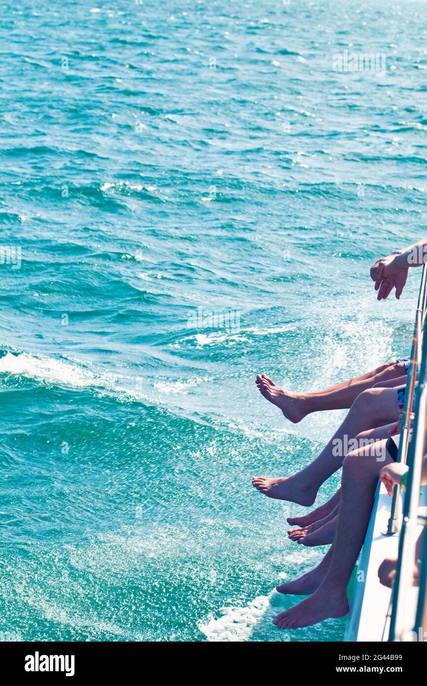 Vue sur les jambes des peuples qui pendaient sur un bateau en mer à Varadero, Cuba Banque D'Images