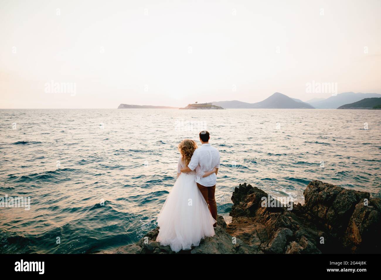 La mariée et le marié se tiennent sur les rochers par la mer et regarder dans la distance Banque D'Images