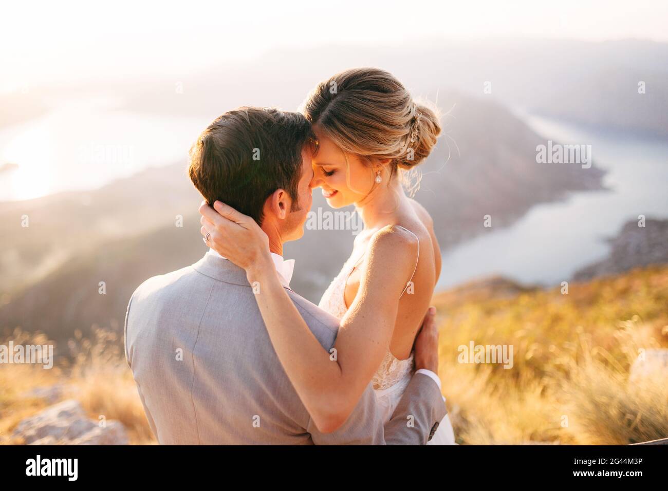 La mariée et le marié assis sur le sommet du mont Lovcen surplombant la baie de Kotor, souriant et embrassant, tendre, gros plan Banque D'Images