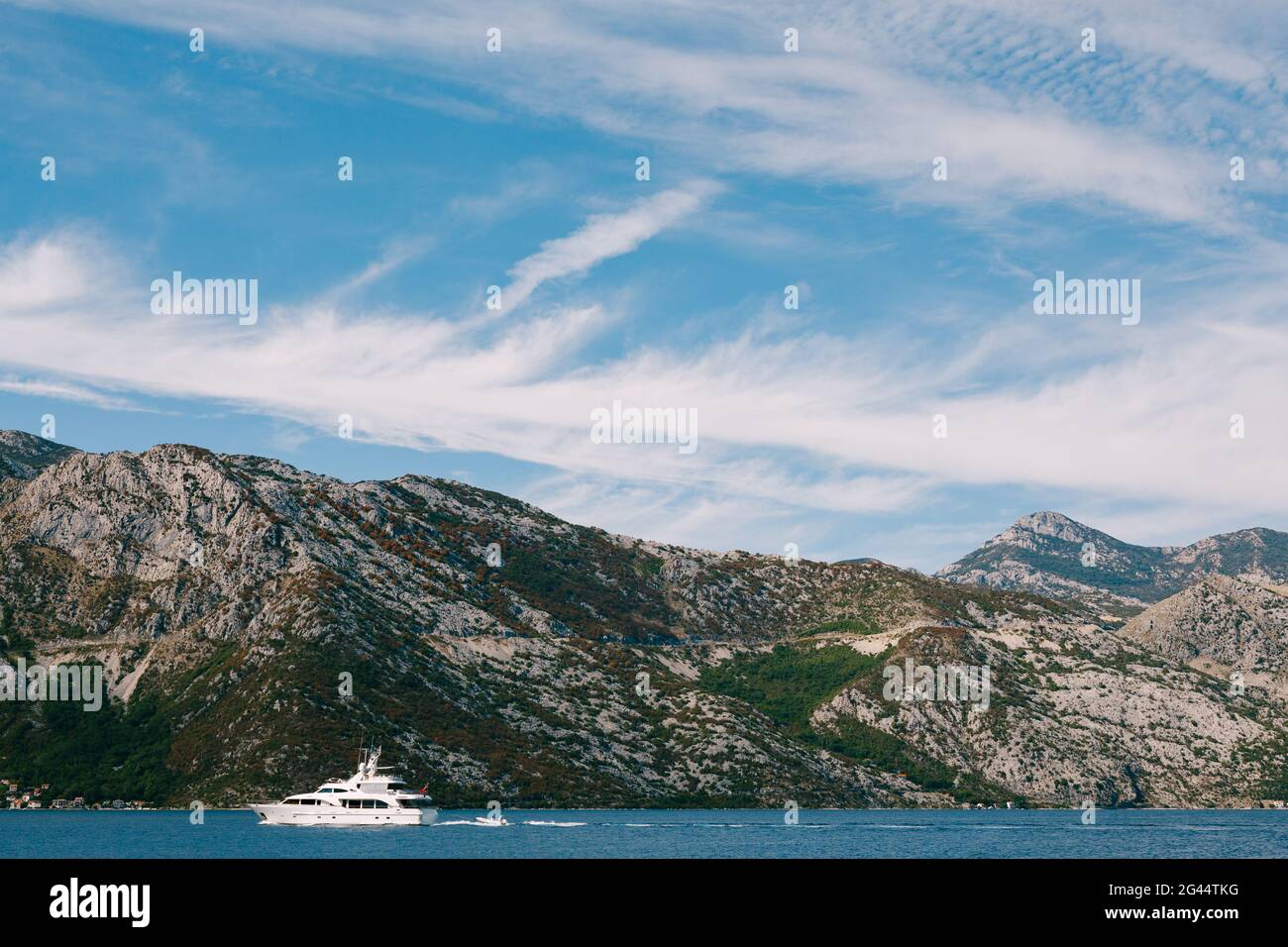 Le yacht blanc de luxe navigue sur la baie de Kotor au Monténégro, sur le fond des montagnes, ciel bleu avec des nuages. Banque D'Images