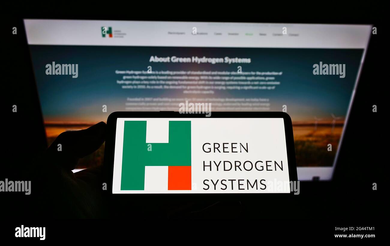 Personne tenant un smartphone avec le logo de la société danoise d'énergie Green Hydrogen Systems COMME sur l'écran en face du site Web. Mise au point sur l'affichage du téléphone. Banque D'Images