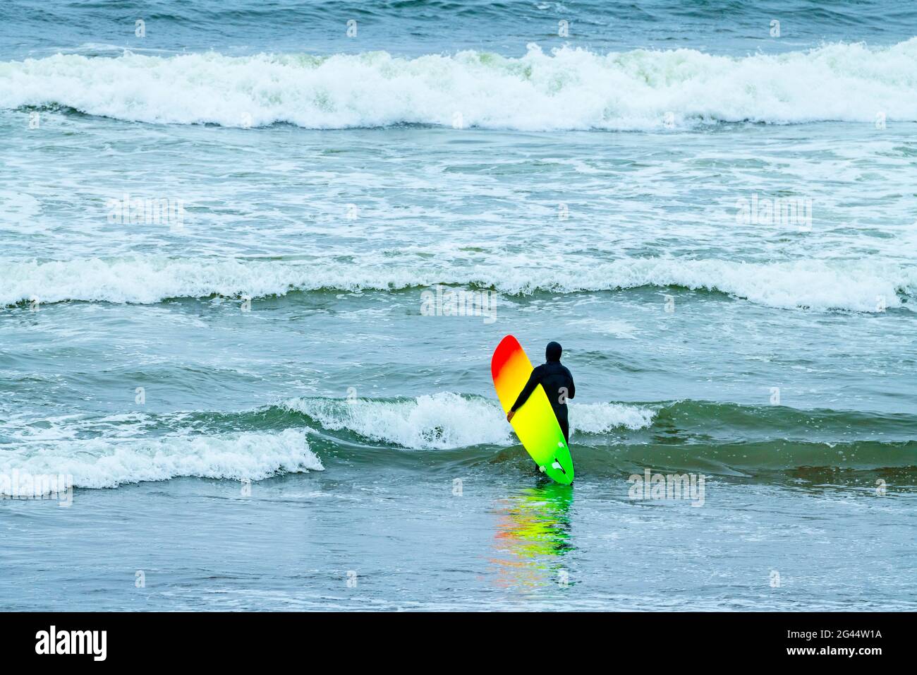 Surfeur avec planche de surf colorée dans l'océan Pacifique, Californie, États-Unis Banque D'Images