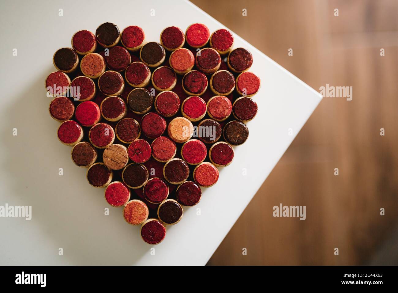 Les bouchons de bouteilles de vin sont alignés en forme de coeur sur un fond blanc. Banque D'Images