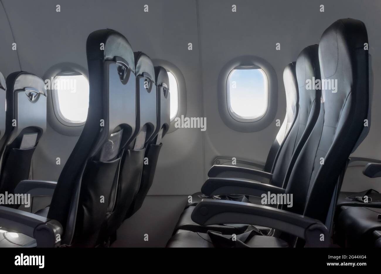 Bel intérieur de cabine d'avion de passager, avec rangées vides de chaises de classe économique ou de fauteuils inclinables. Banque D'Images