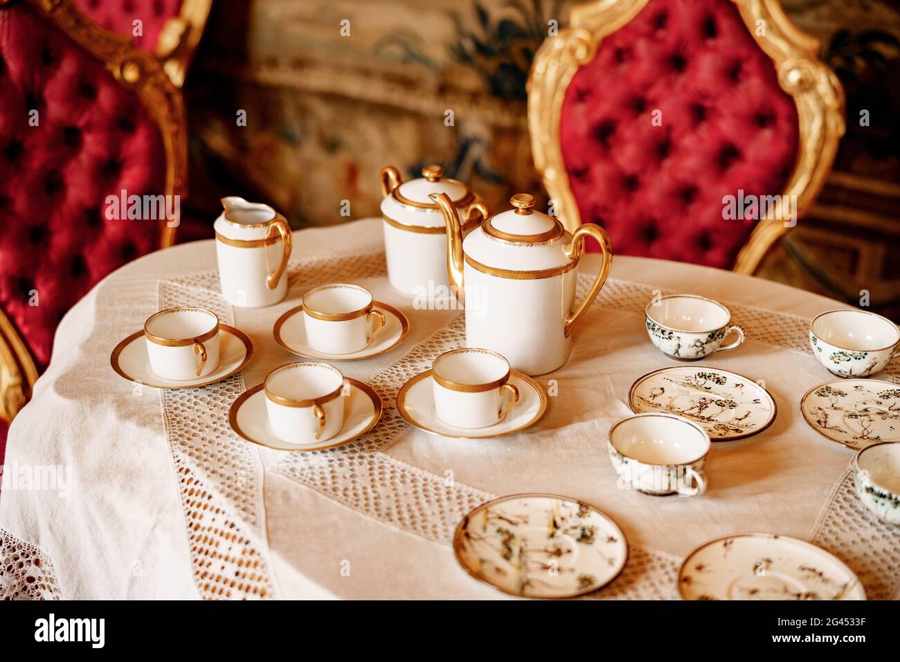 Gros plan sur une table en dentelle blanche avec chaises rouges en peluche. Banque D'Images