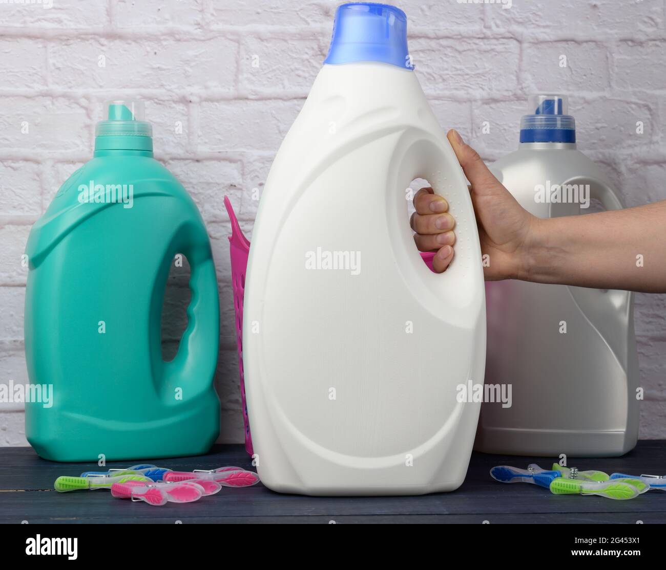 Main de femme tenant une grande bouteille en plastique blanc avec un détergent pour laver les vêtements Banque D'Images