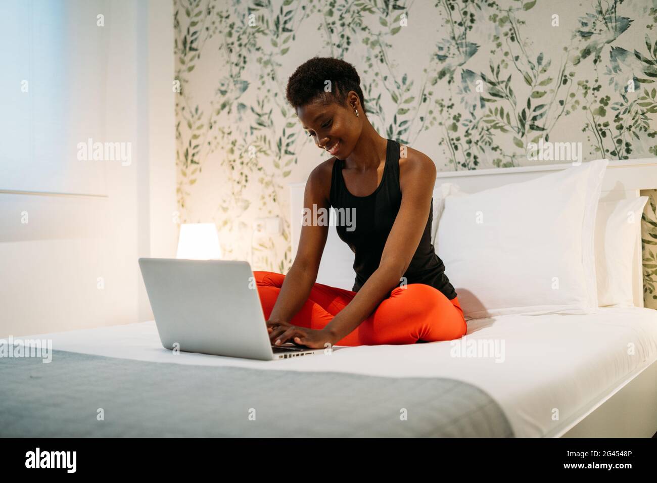 Belle femme noire travaillant avec son ordinateur portable sur son lit à la maison Banque D'Images