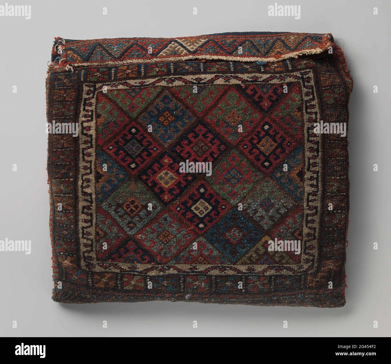 Valise, décorée de fleurs en grille marron et en crochet. Sac à selle, Jaffi Kurdistan Mossoul. Le milieu de terrain est divisé en diamants par une grille marron, tous remplis de fleurs égales en forme de diamant et brisées. Le bord central est divisé en rectangles avec une fleur. Au sommet d'une barbe divisée en différentes couleurs. Tissu plat à l'arrière avec rayures de différentes couleurs. Banque D'Images