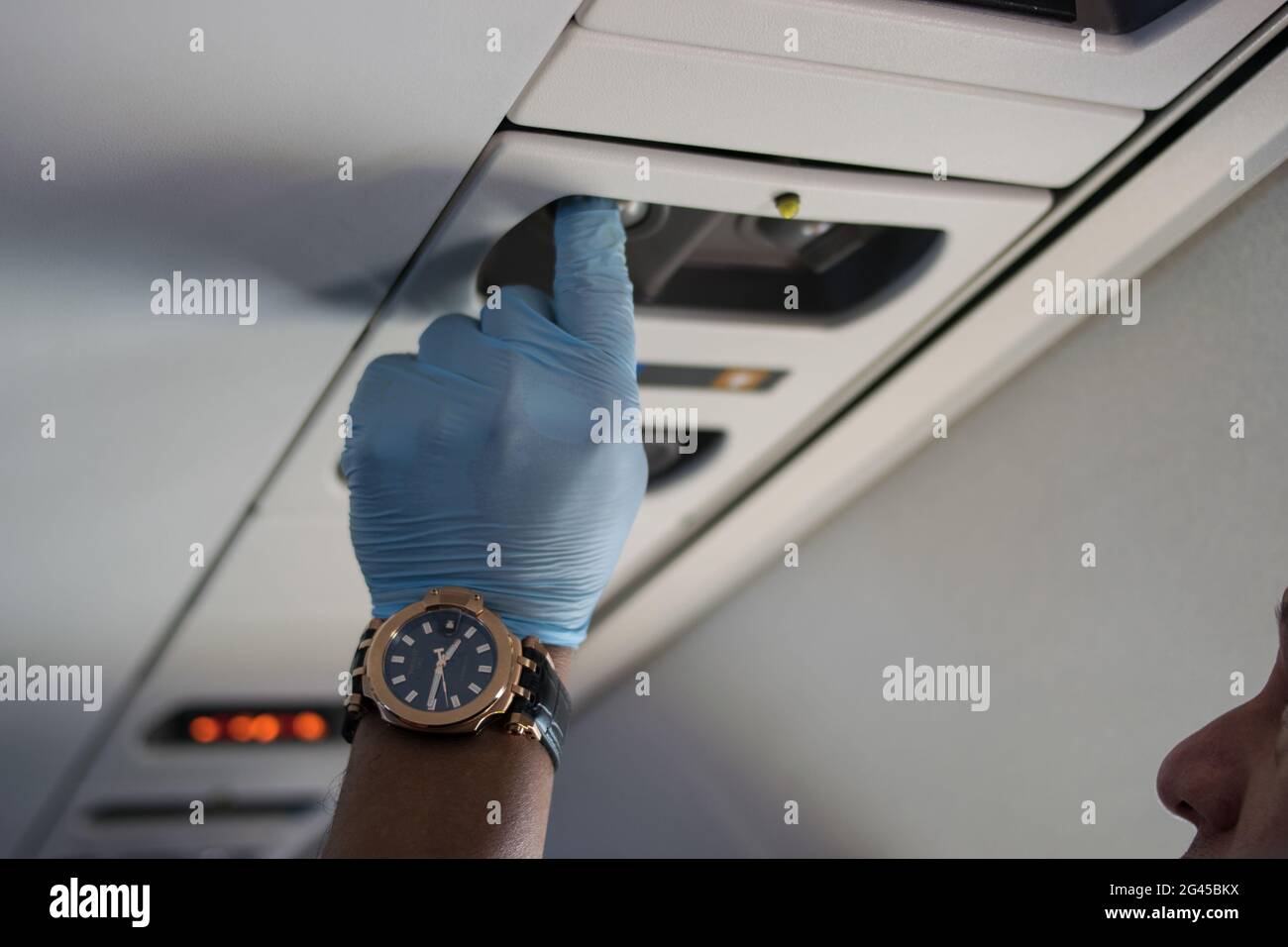 Un homme utilisant un ensemble de gants chirurgicaux appuie sur un bouton dans la cabbine de l'avion alors que le gouvernement colombien a parrainé des vols de rapatriement gratuits vers la Colombie admist le nouvel épidémie de coronavirus (COVID-19) et le résultat de vols commerciaux au sol, à Miami, Floride, U.S, le 7 août, 2020. Banque D'Images