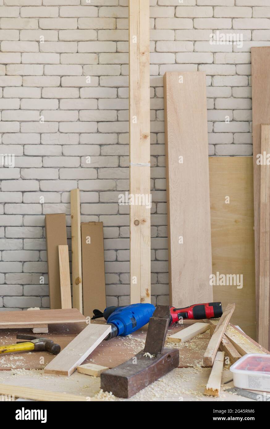 Le semoir électrique bleu a été laissé de côté pendant le freinage du déjeuner. Un bureau rempli d'outils à main et de piles de bois. Atmosphère de travail dans la salle d'atelier. Banque D'Images