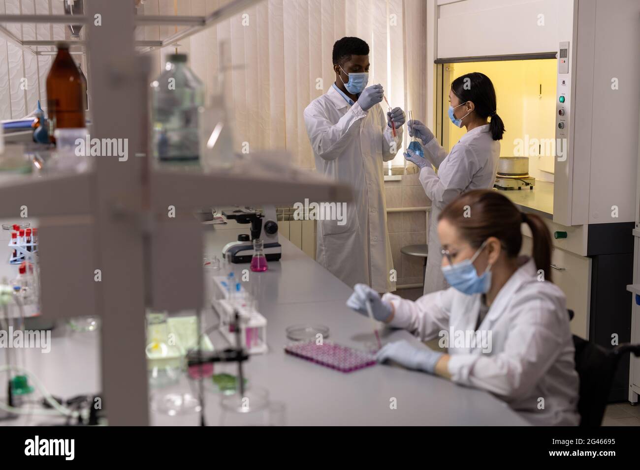 Groupe de jeunes scientifiques travaillant avec des fluides dans des flacons en laboratoire scientifique Banque D'Images