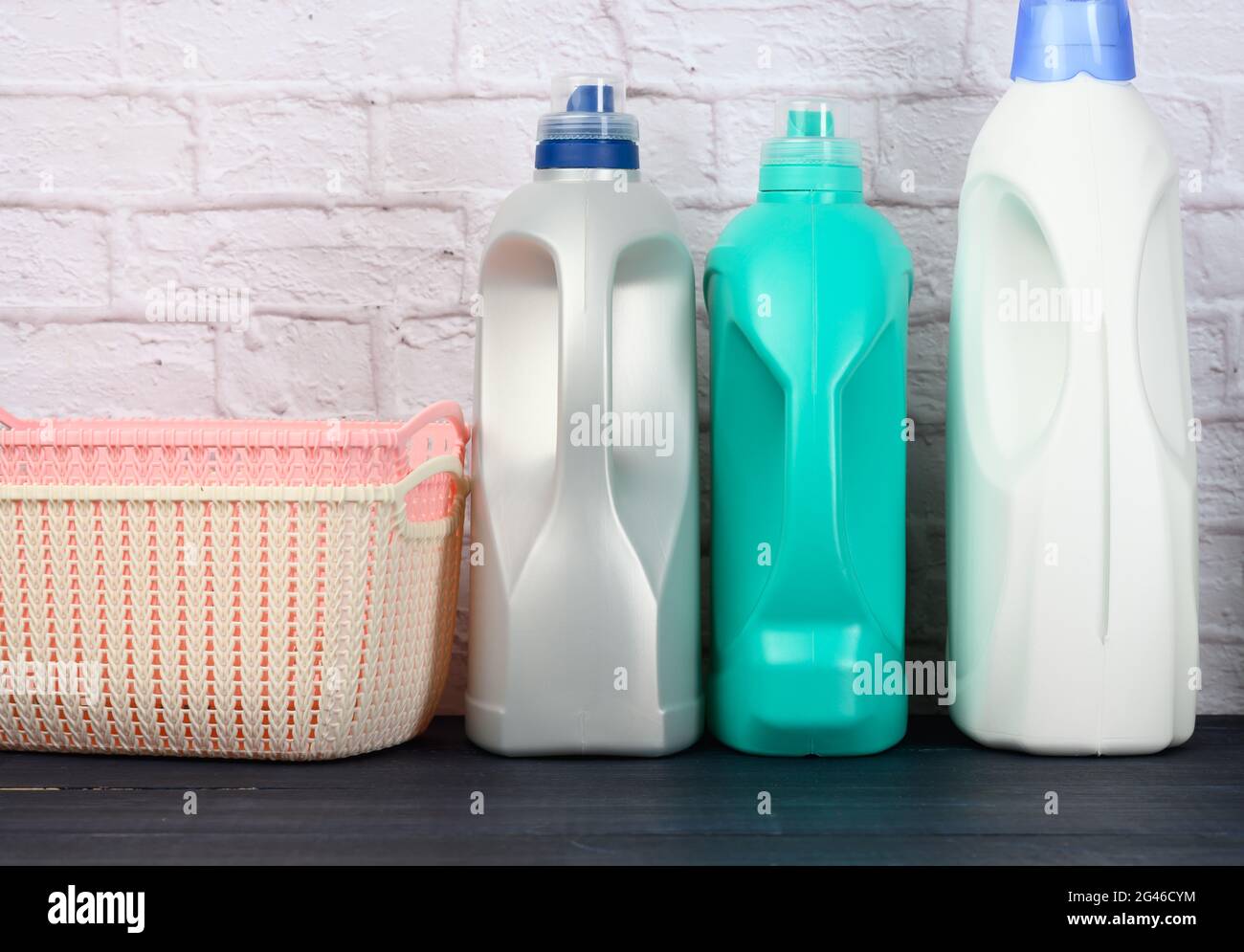 Les bouteilles de détergent liquide et les paniers à linge en plastique sont vides sur une table bleue en bois Banque D'Images