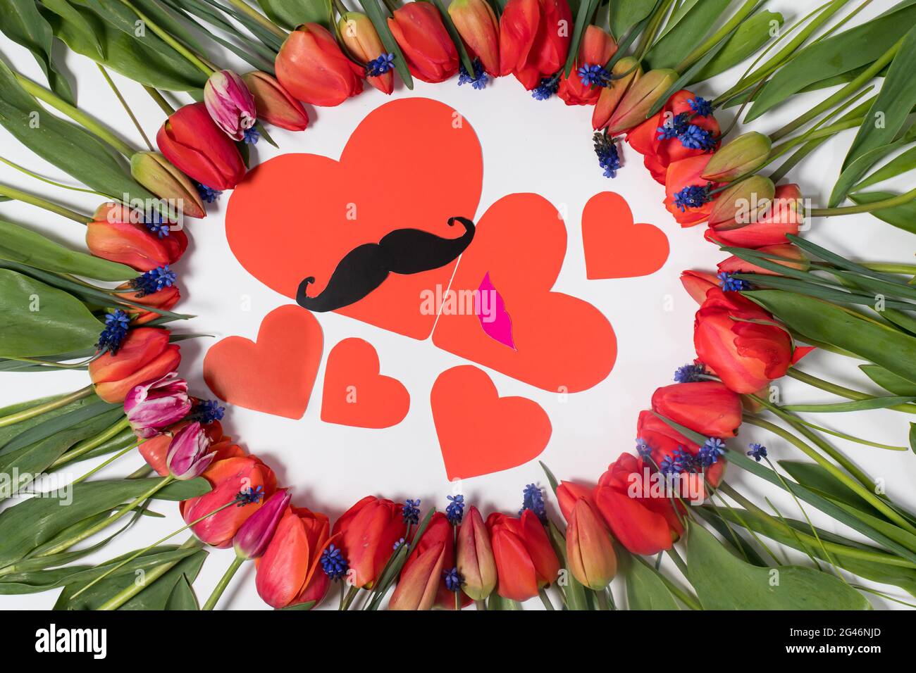 Carte postale à la fête de la famille - un cadre floral de tulipes et une graine de coeur - maman, papa avec une moustache et leurs enfants. Banque D'Images