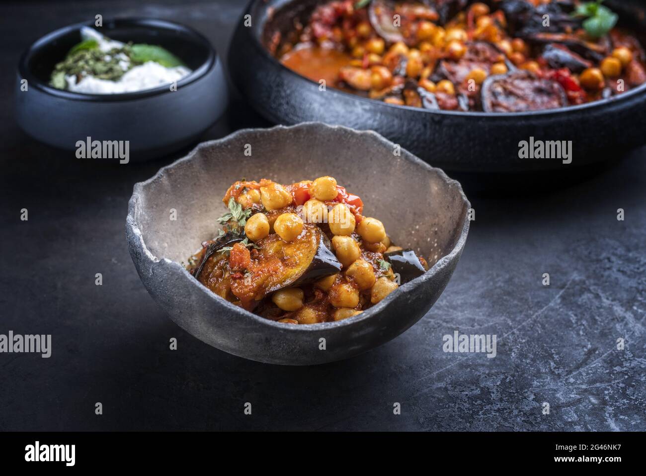 Maghmour au ragoût d'aubergines libanaises cuites lentement, servi avec des pois chiches et des yaourts dans un cadre rustique Banque D'Images