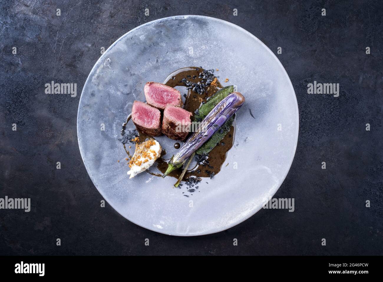 Filet traditionnel à dos de lièvre sauvage de style moderne braisé avec de l'aubergine et des quenelles au jus de gibier servi comme vue de dessus sur un desig Banque D'Images