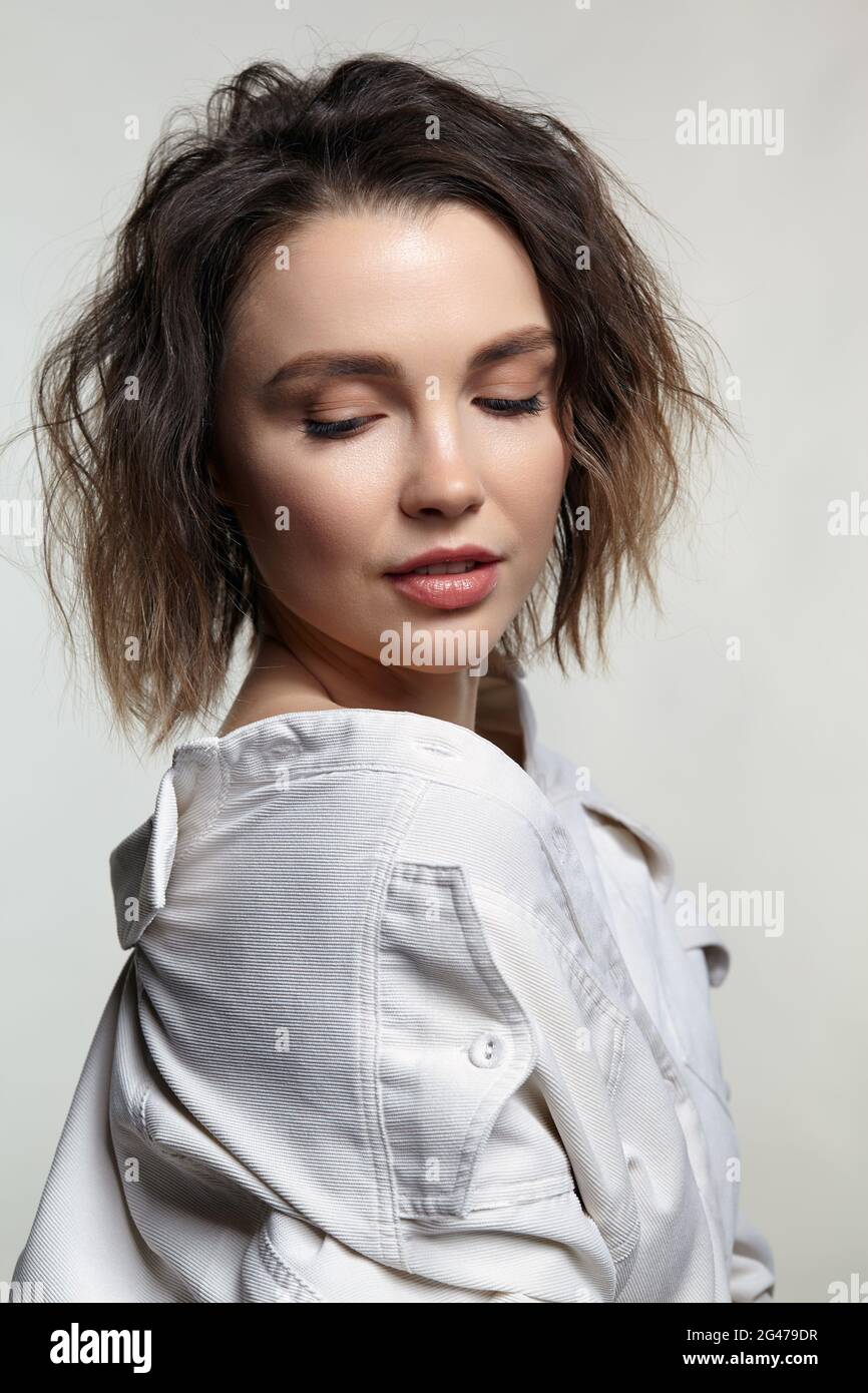 Portrait de la jeune femme avec les yeux en déposition. Femme posant dans une chemise en velours côtelé blanc laiteux. Banque D'Images