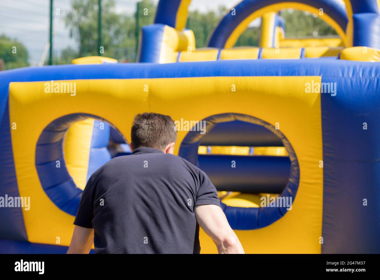 Un homme court à l'intérieur d'un obstacle gonflable. Aire de jeux gonflable. Des vacances actives en été. Banque D'Images