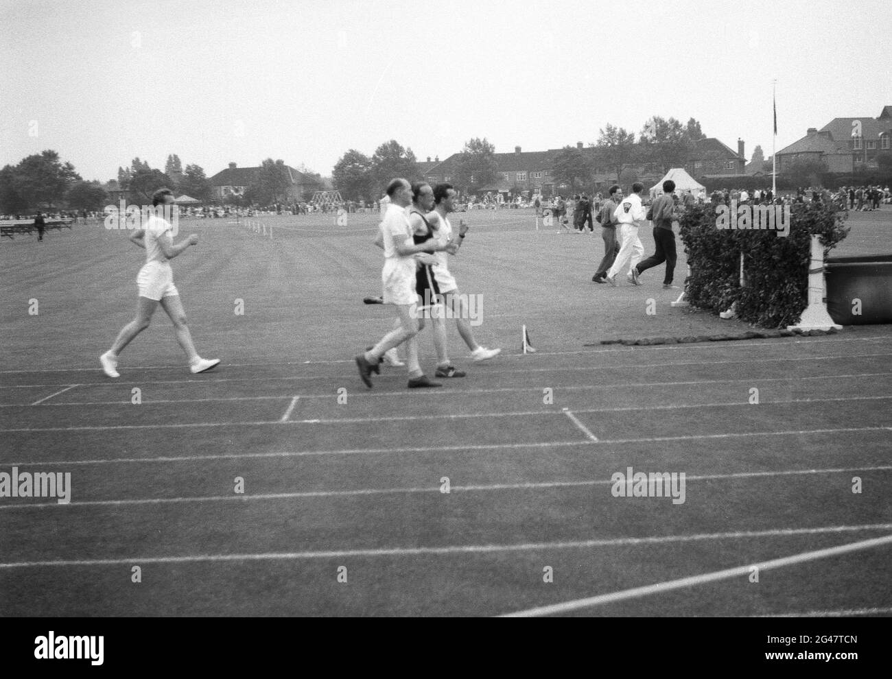 1954, historique, à l'extérieur sur une piste de gazon, les hommes marcheurs de course en compétition dans une journée de sports de la fonction publique, Angleterre, Royaume-Uni. La course à pied ou à pied est une discipline de longue distance en athlétisme, où un pied doit - ou semble - être en contact avec le sol à tout moment. Banque D'Images