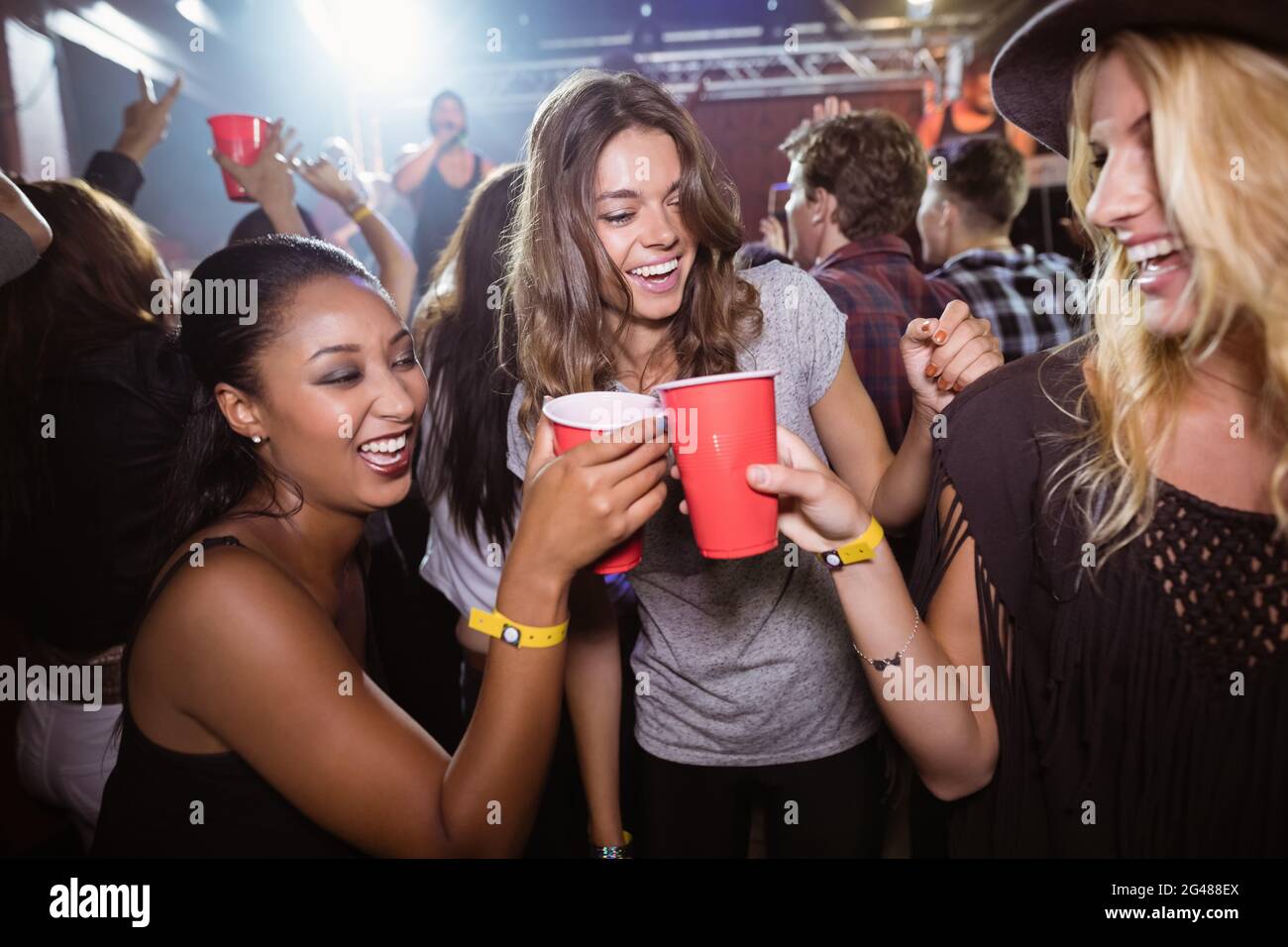 Female friends toasting tasses jetables en club Banque D'Images