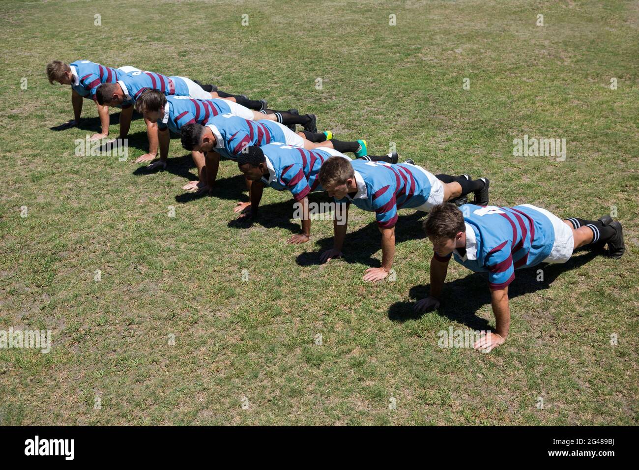 Vue à grand angle des joueurs qui font pousser ats Grassy Field Banque D'Images