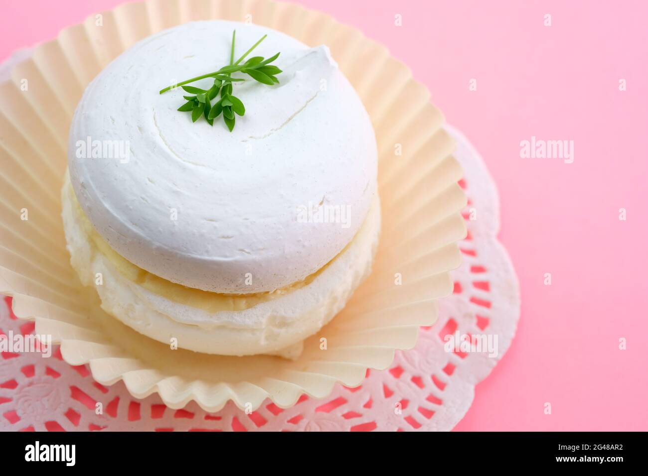Gâteau meringue et crème au beurre. Gâteau de crème aux protéines aéré farci de crème fouettée sur fond rose. Banque D'Images