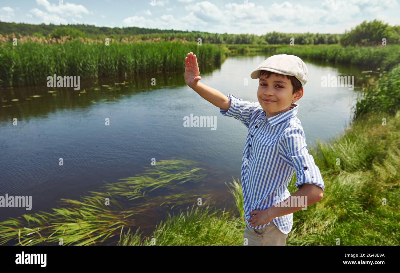 Un adorable garçon souriant se coucou, debout sur le fond de la rive de la  rivière. Enfant garçon en vacances d'été dans la campagne Photo Stock -  Alamy