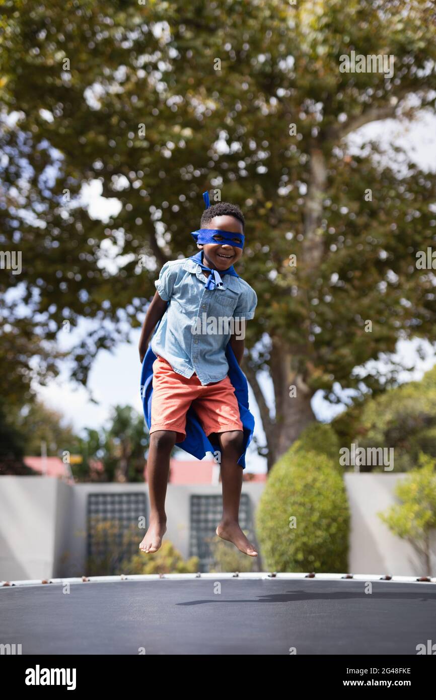 Garçon en costume de super-héros sautant sur trampoline Photo Stock - Alamy