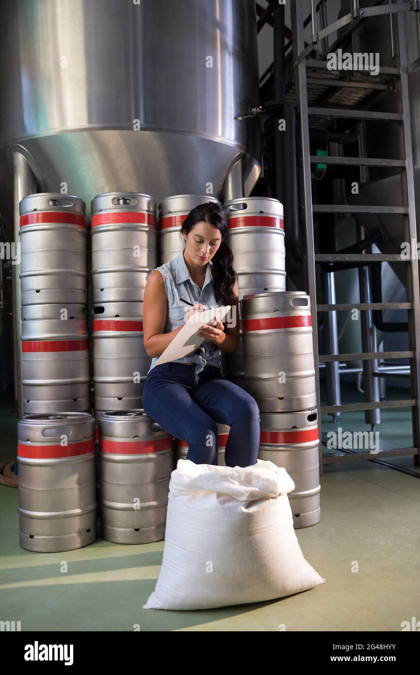 Travailleur féminin writing on clipboard in factory Banque D'Images