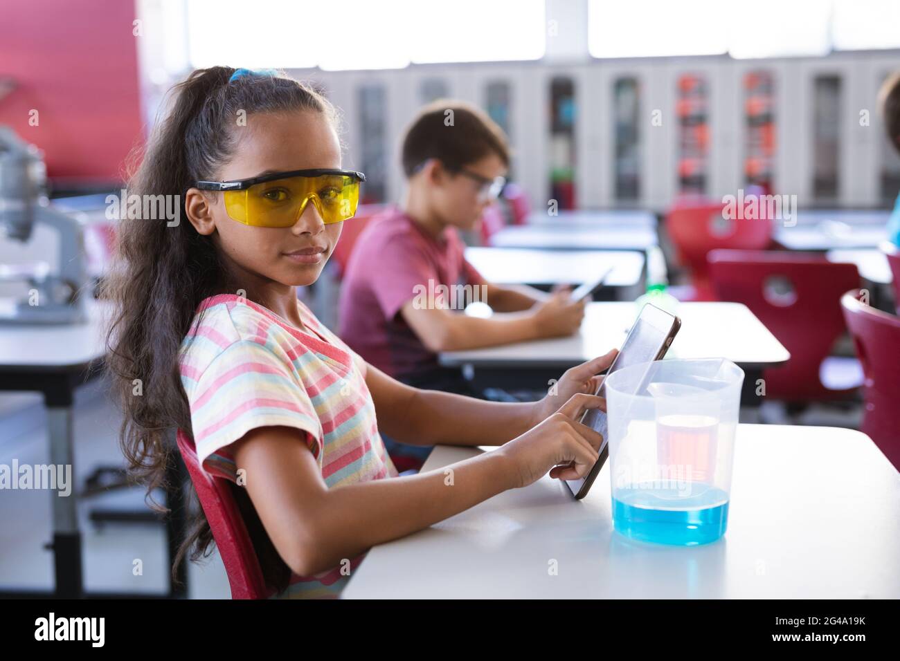 Portrait d'une fille afro-américaine tenant une tablette numérique en classe scientifique au laboratoire Banque D'Images