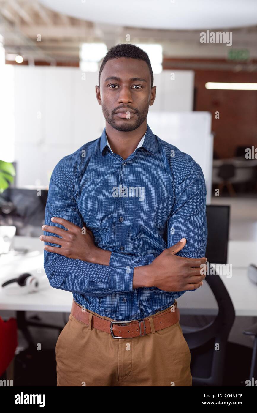 Portrait d'un homme d'affaires afro-américain debout au bureau avec les bras croisés regardant l'appareil photo Banque D'Images