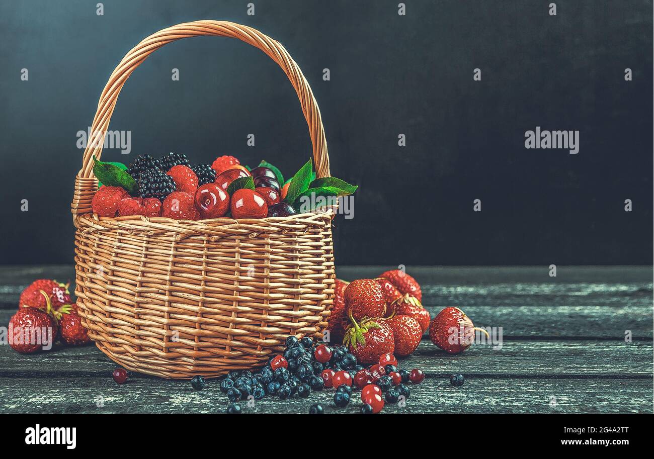 Baies de forêt fraîches dans un panier sur fond en bois noir avec espace de copie Banque D'Images