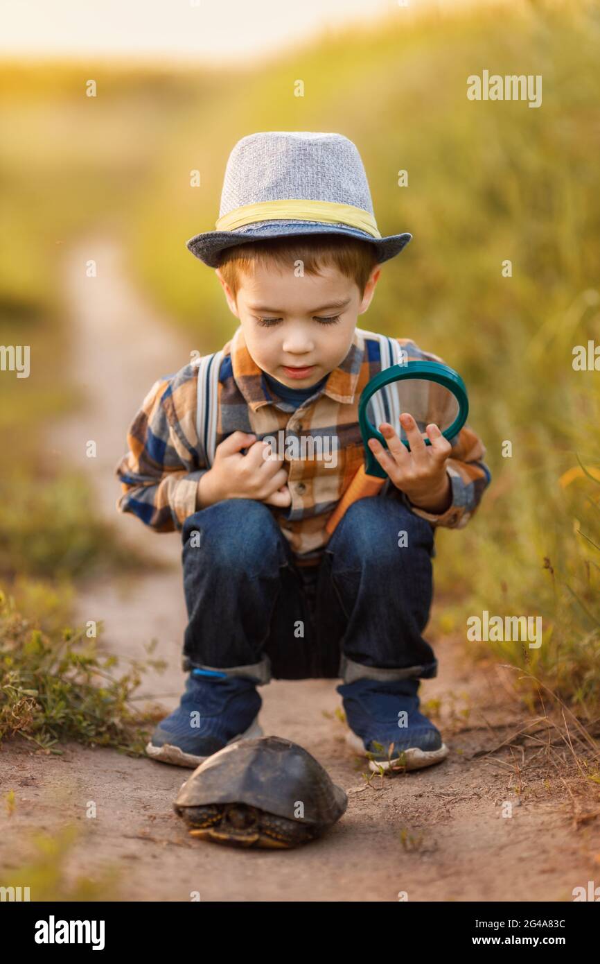 petit garçon explorant la nature dans la prairie avec une loupe Banque D'Images